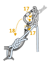 Climber on an anchor hanging on a rope tied through the rappel ring removing rest of his gear from the anchor